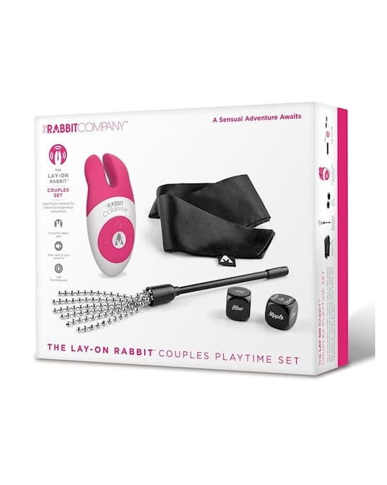 A white rectangular box sits upright with a picture on the front of it which includes a pink rubber looking bunny shaped object, two black cubes and a piece of black satin.