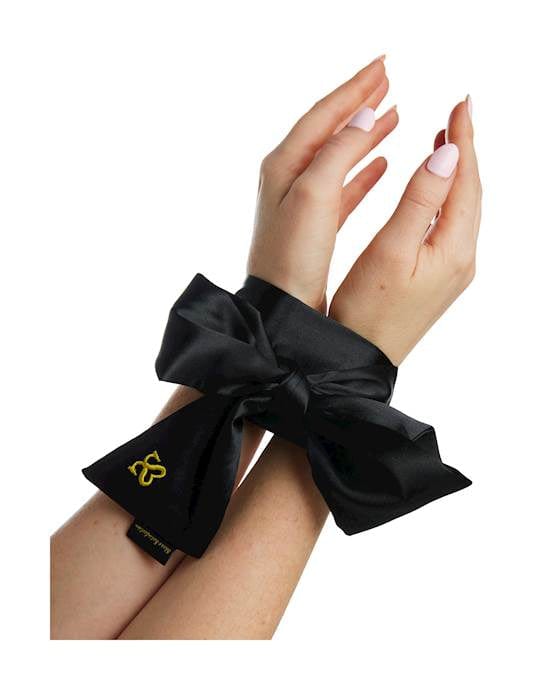 Woman's hands shown from the elbow down and tied together with a black satin ribbon.