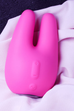 Open image in slideshow, bright pink coloured toy that looks like a cute bunny sitting upright facing forward with control buttons displayed leaning on pale pink draped material background.
