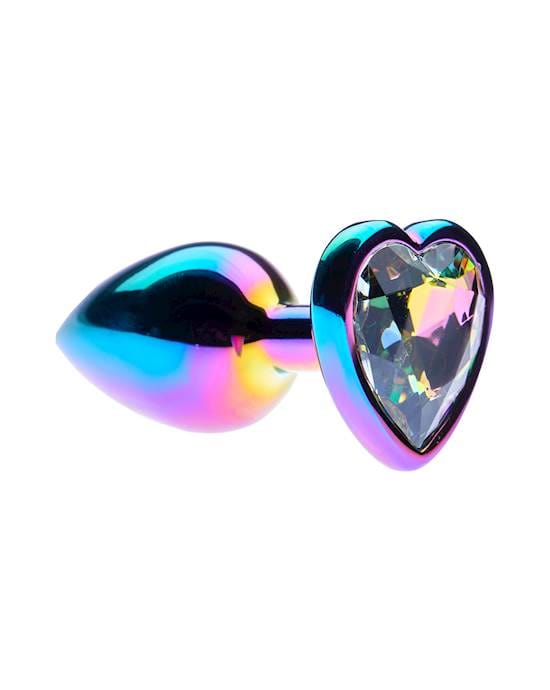 A shiny metallic object which has a heart shaped diamante on one end and a knobby end which is rainbow coloured.
