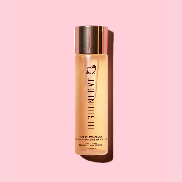 Bottle of High on Love massage oil on a pale pink background. The bottle is clear and the lid is shiny gold.