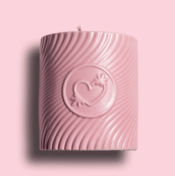Pink candle with a heart design on a pink background