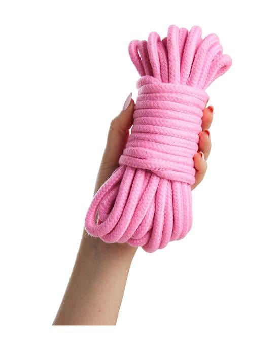 A woman's hand on a white background clasping a neatly tied bunch of light pink thick thread.
