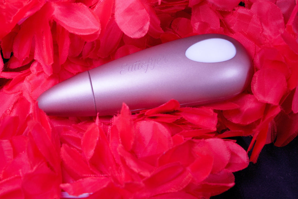 Copper coloured product laying face down showing a white oval on it's top and the brand name engraved on a red feather back drop.