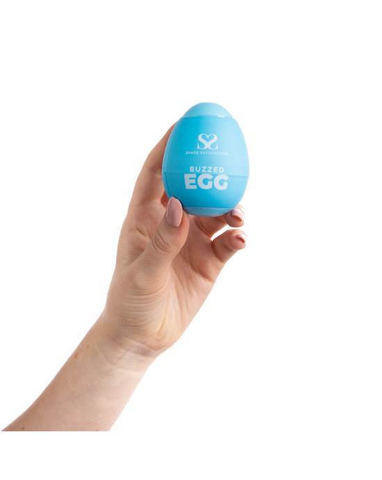 A hand and forearm holding a pale blue egg which has writing and a logo printed on it.