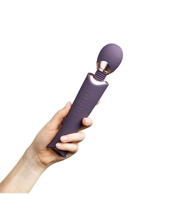 A woman's hand is holding a purple wand or microphone looking object that is joined in the middle with a shiny gold-plating.